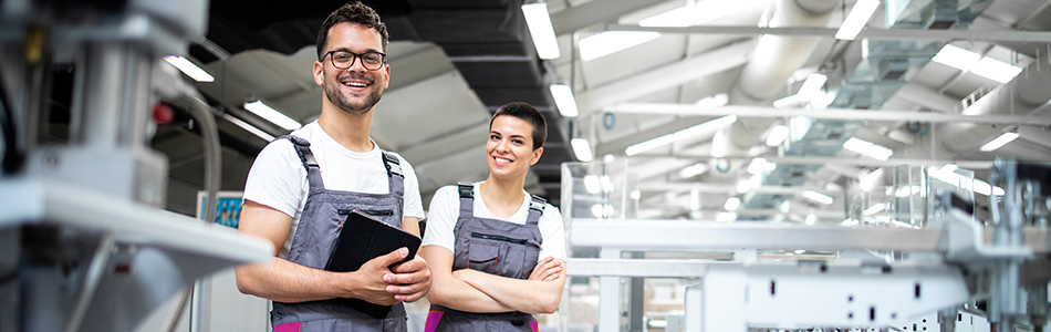Técnicos de impresión con tableta junto a maquinaria industrial