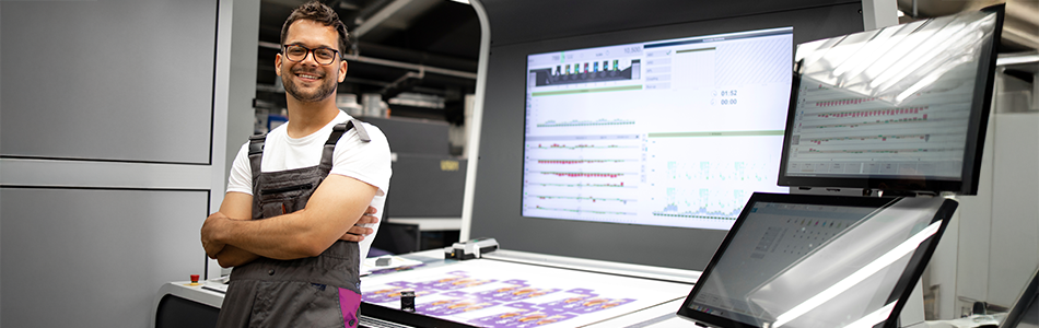 Técnico de impresión junto a maquinaria digital y monitores de producción